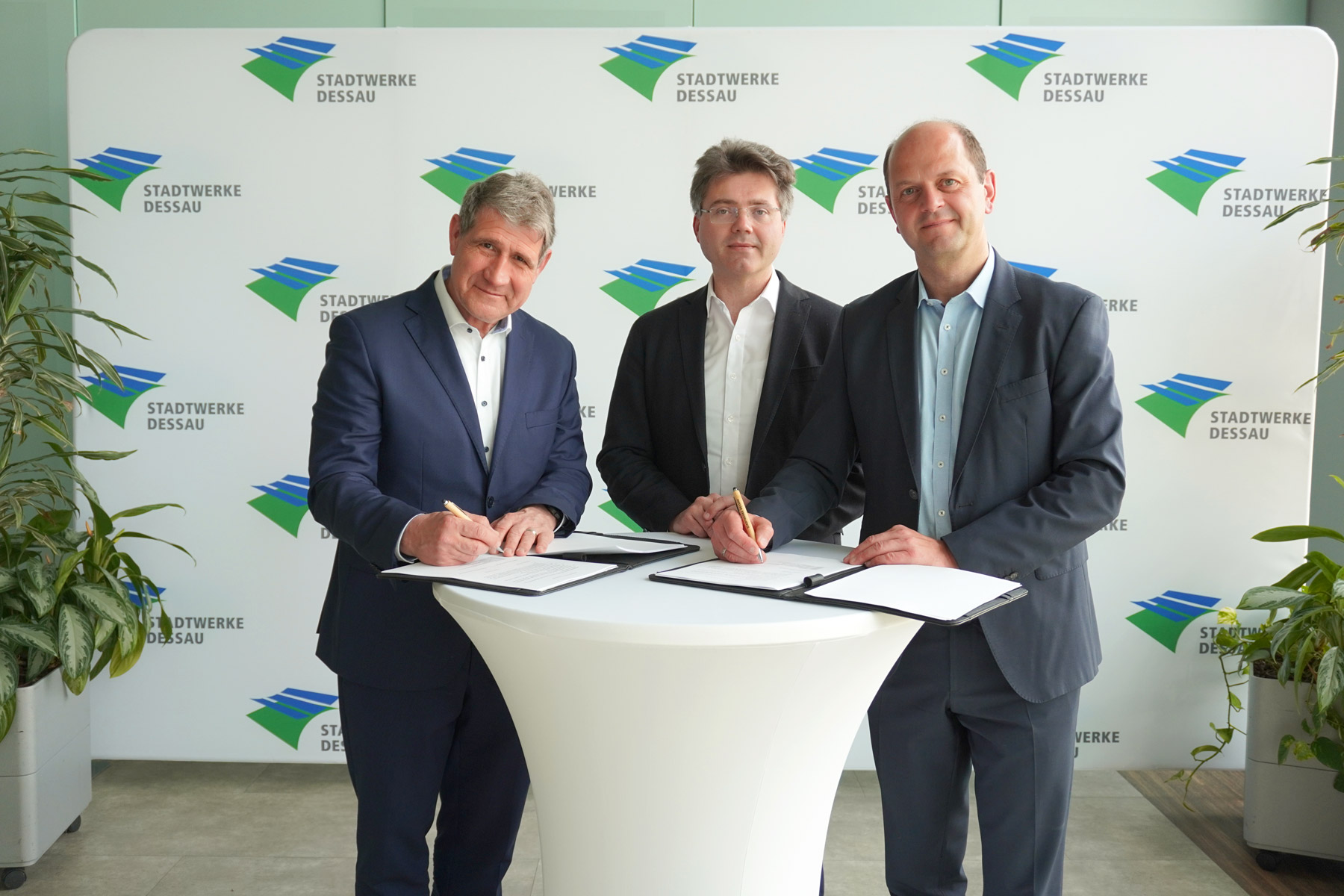 Three men signing heat offtake agreement for the Carbon Removal Park Dessau