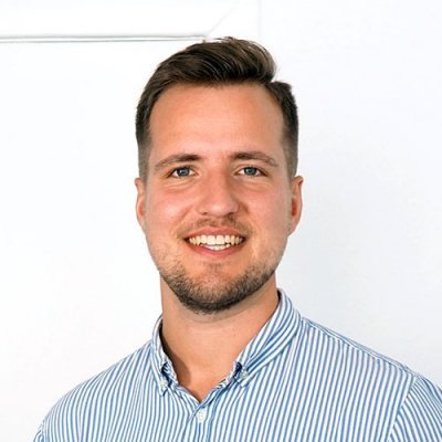 Portrait of a smiling man, Christoph Janyska, wearing a shirt striped white and blue.